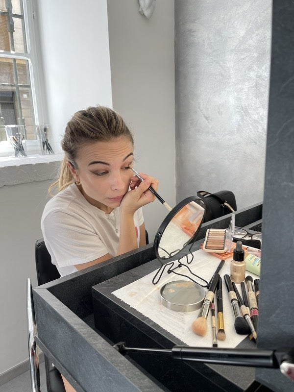 Una ragazza si stende l'ombretto da sola con pennello e specchietto, nello studio di Federica